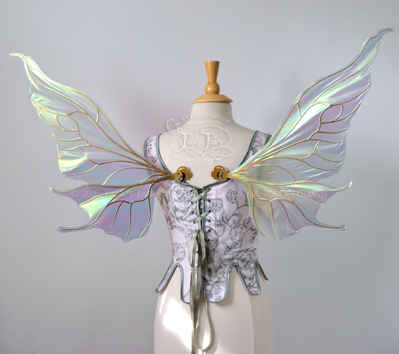 Sheer green iridescent fairy wings with wavy tips and gold veins, worn on a dress form, back view