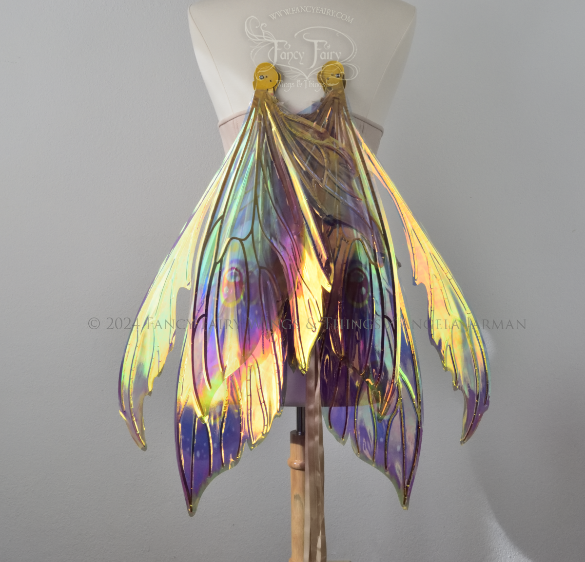 Extra large rainbow iridescent fairy wings with antennae and gold veins, worn on a dress form, in resting position, back view