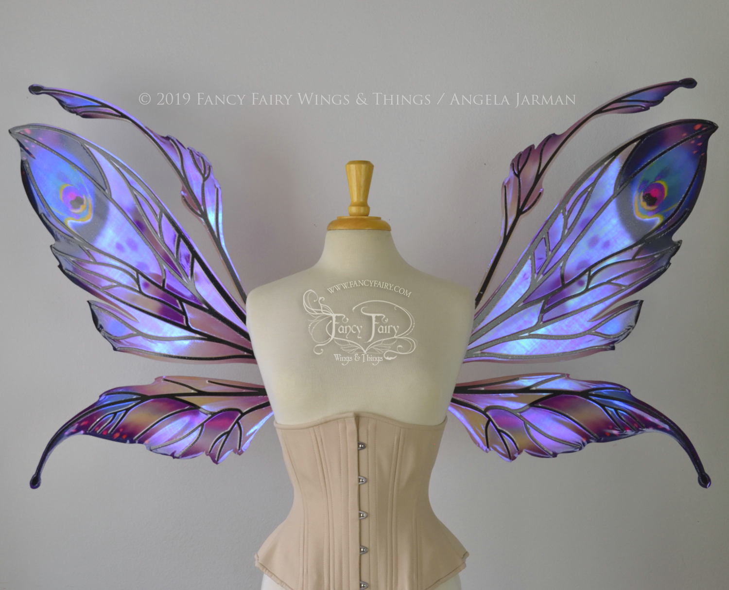Front view of a dress form wearing an underbust corset & extra large iridescent fairy wings with mauve purple & blue color pattern