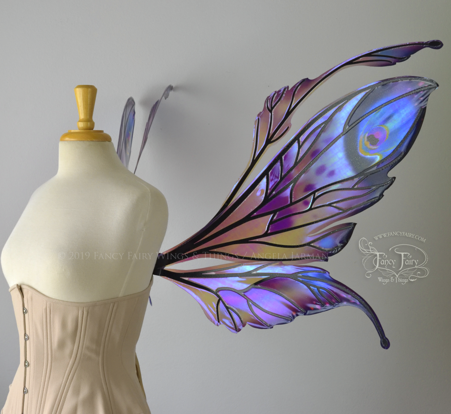 Right side view of a dress form wearing an underbust corset & extra large iridescent fairy wings with mauve purple & blue color pattern 