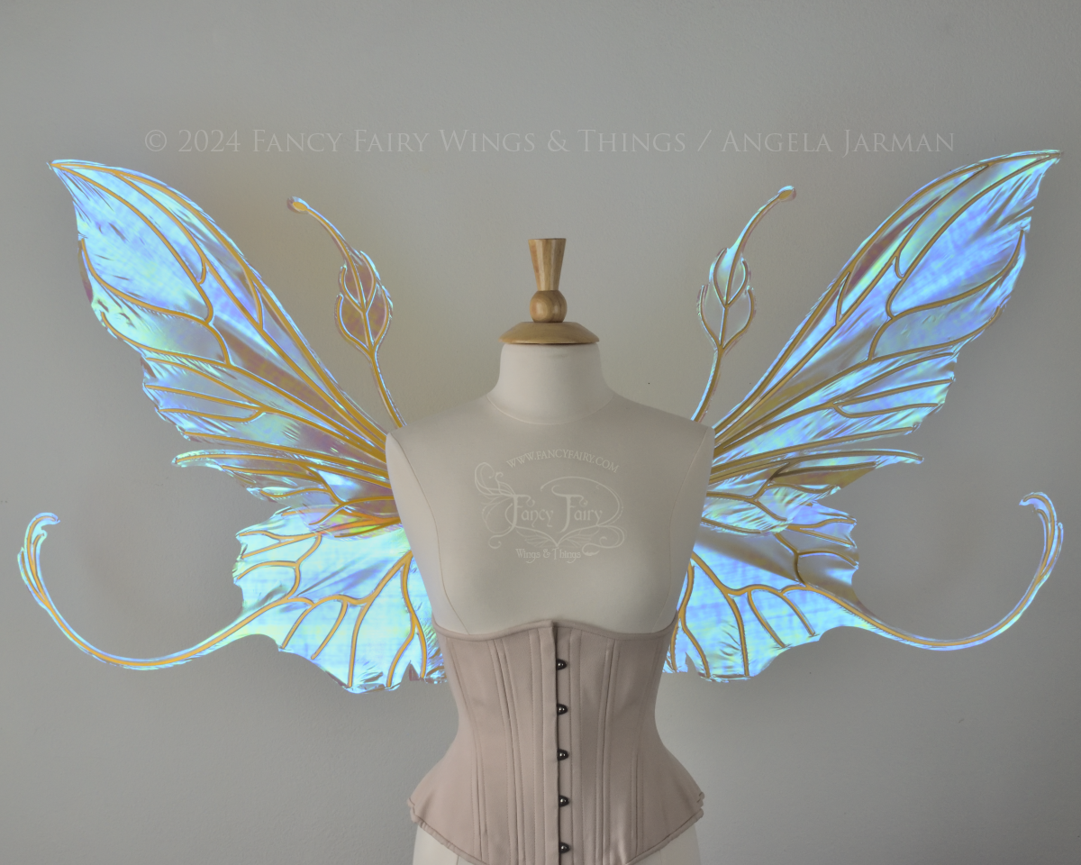 Front view of a dress form wearing an underbust corset & large blue / peach iridescent fairy wings with elongated upper panels & antennae with bottom panels that have a tail curving upwards, gold veins