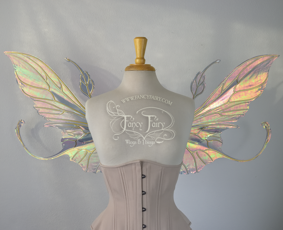 Front view of an ivory dress form wearing an alabaster underbust corset & large orange/green  iridescent fairy wings with elongated upper panels & antennae with bottom panels that have a tail curving upwards, gold veins