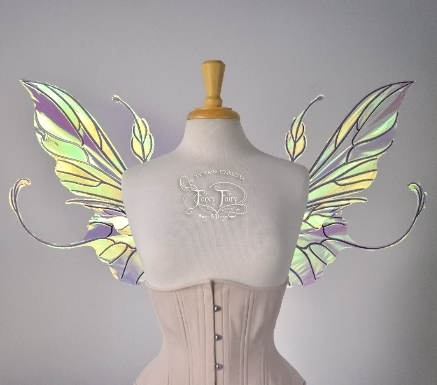 Front view of an ivory dress form wearing an alabaster underbust corset & large clear iridescent fairy wings with elongated upper panels & antennae with bottom panels that have a tail curving upwards, black veins