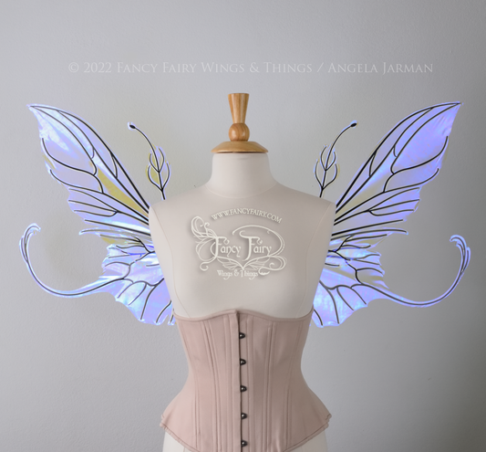 Front view of an ivory dress form wearing an alabaster underbust corset & large clear ultraviolet iridescent fairy wings with elongated upper panels & antennae with bottom panels that have a tail curving upwards, black veins