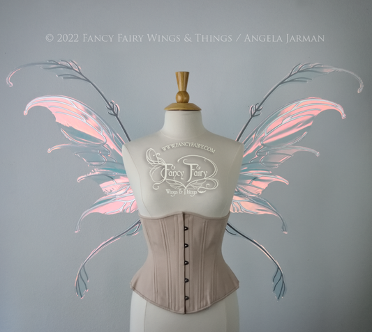 Front view of a dress form wearing an underbust corset & 'Fauna' transparent pink iridescent fairy wings with downward curved tips, antennae & wispy 'tails', with silver veining