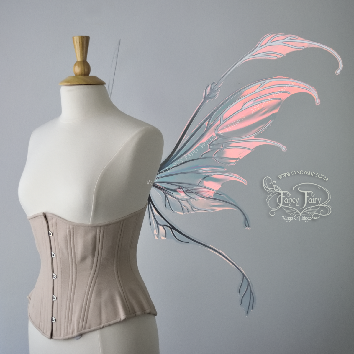 Right side view of a dress form wearing an underbust corset & 'Fauna' transparent pink iridescent fairy wings with downward curved tips, antennae & wispy 'tails', with silver veining