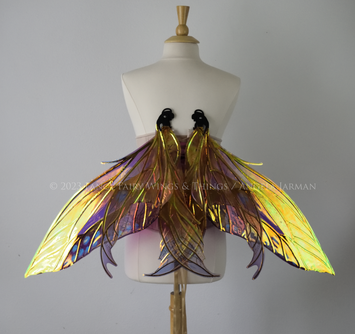 Back view of large burgundy and peach pink iridescent fairy wings with 3 panels on each side, pointed tips, lots of vein detail, worn on a dress form, in resting position.