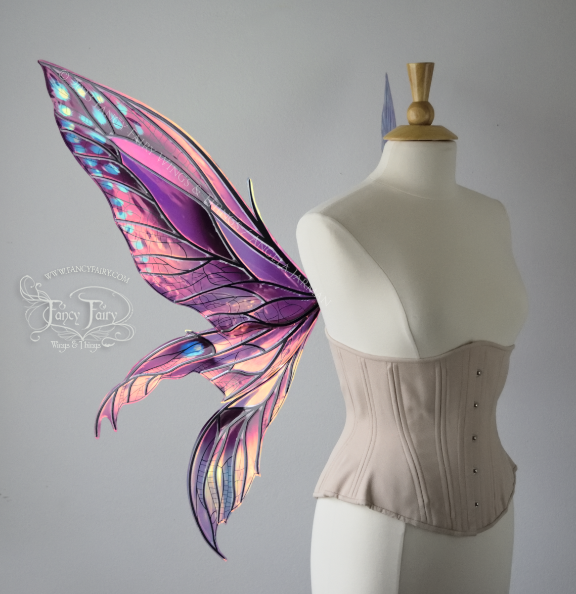 Left 3/4 view of large burgundy and peach pink iridescent fairy wings with 3 panels on each side, pointed tips, lots of vein detail, worn on a dress form.