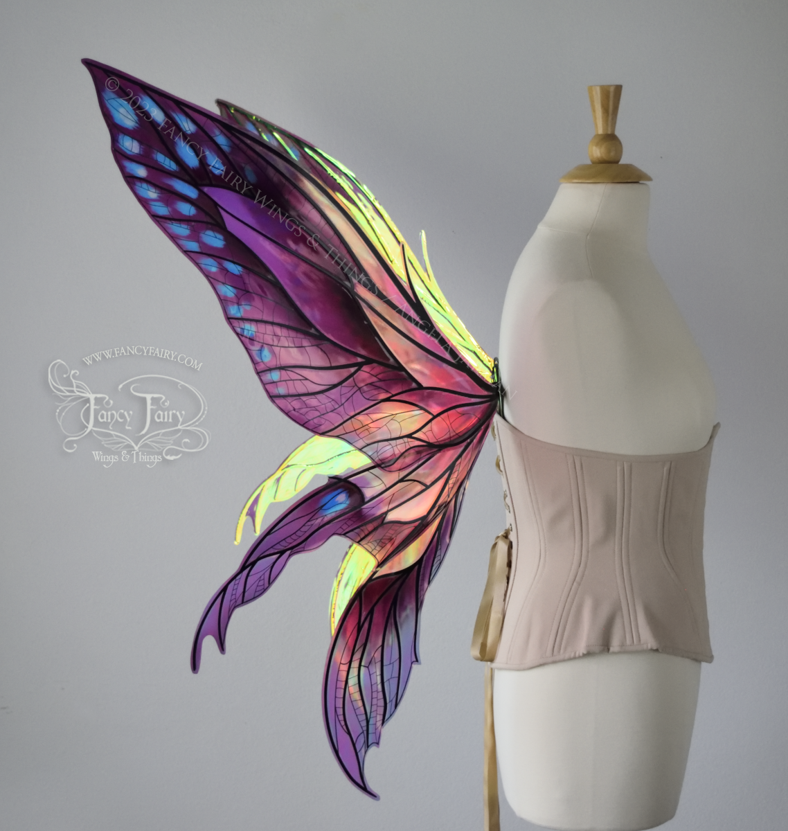 Left side view of large burgundy and peach pink iridescent fairy wings with 3 panels on each side, pointed tips, lots of vein detail, worn on a dress form.