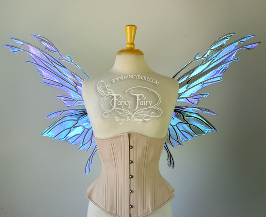 Front view of an ivory dress form wearing an alabaster underbust corset & purple / blue iridescent fairy wings with elongated upper panels with petal like appendages at the tips & antennae, the veins are black
