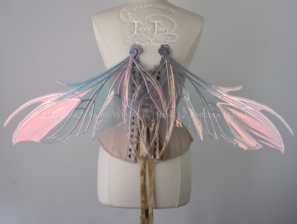 Back view of iridescent pink / orange fairy wings with spikey silver veins, worn by a dress form in resting position