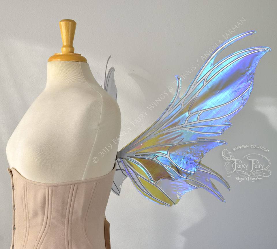 Right side view of a dress form wearing an underbust corset & purple / blue iridescent fairy wings with a spikey shape, with silver veins