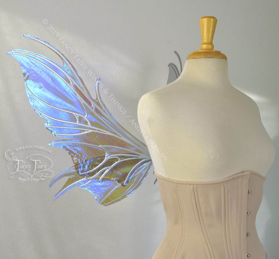 Left side view of iridescent blue / purple fairy wings with spikey silver veins, worn by a dress form