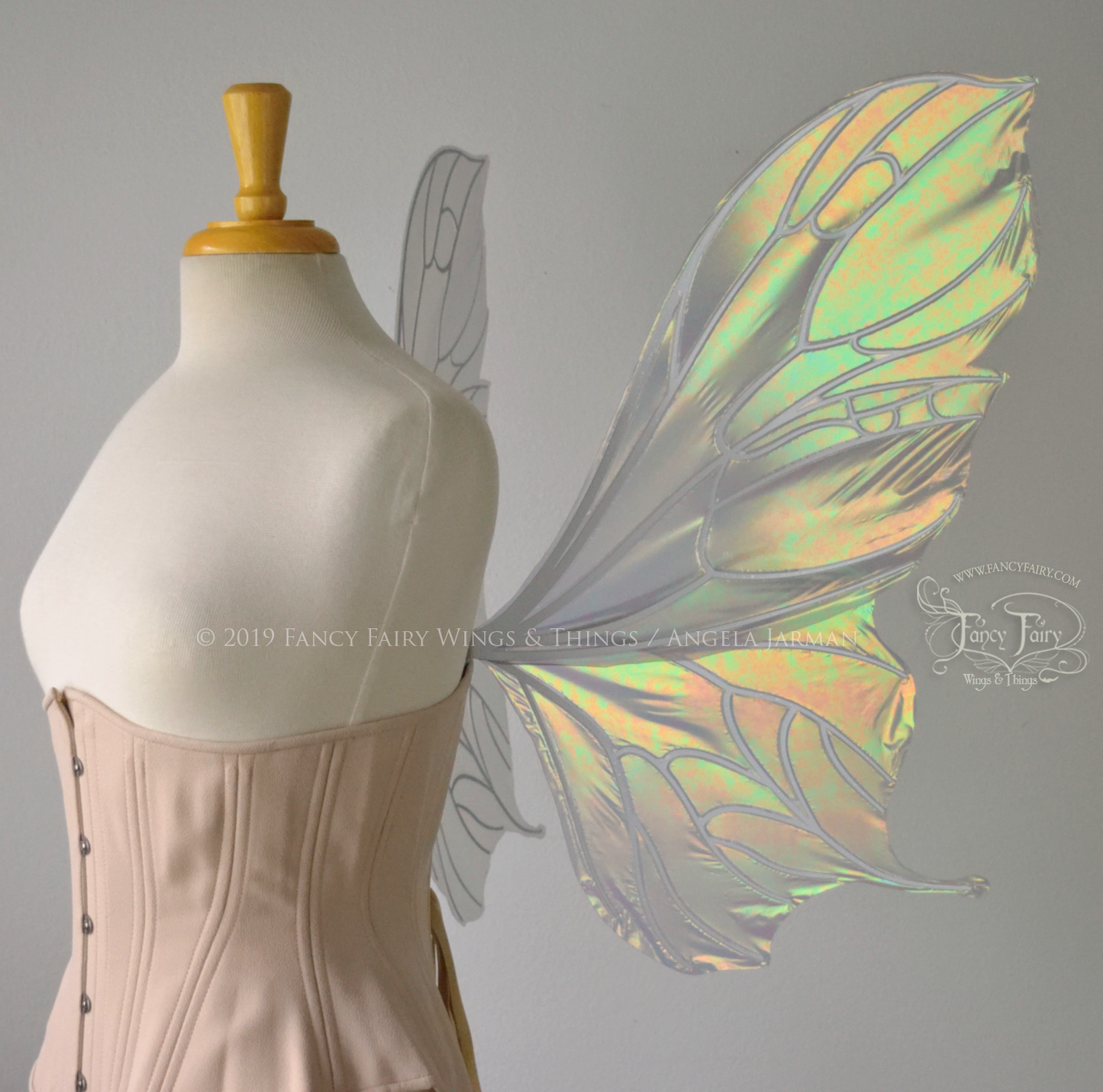 Right view of an ivory dress form wearing an alabaster underbust corset & large iridescent fairy wings with a sort of butterfly shape. The veins are white