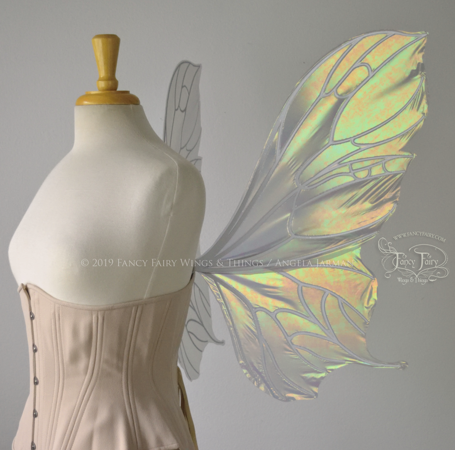 Right view of an ivory dress form wearing an alabaster underbust corset & large iridescent fairy wings with a sort of butterfly shape. The veins are white