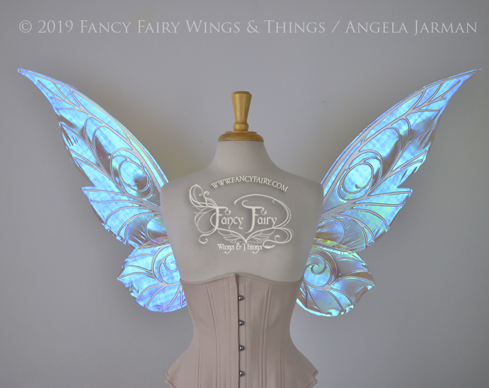 Front view of transparent blue iridescent Tinker Bell inspired fairy wings with swirly white veins, displayed on a dress form